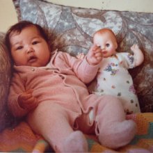 Bliss as a baby sitting with a doll